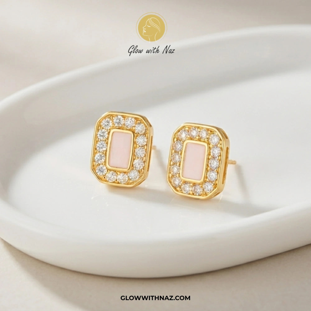 A pair of gold rectangular stud earrings with pale pink inlays and clear crystal borders, displayed on a white ceramic dish. The brand logo 'Glow with Naz' is visible at the top, and the website 'GLOWWITHNAZ. studs earrings, small earrings, girls earrings, simple earrings, earrings for girls, black earrings, earrings, ear rings, earrings tops, stud earrings, tops earrings, aesthetic earrings, hoop earrings, drop earrings, diamond earrings, pink earrings, green earrings, ear ring, earrings for women, flower 