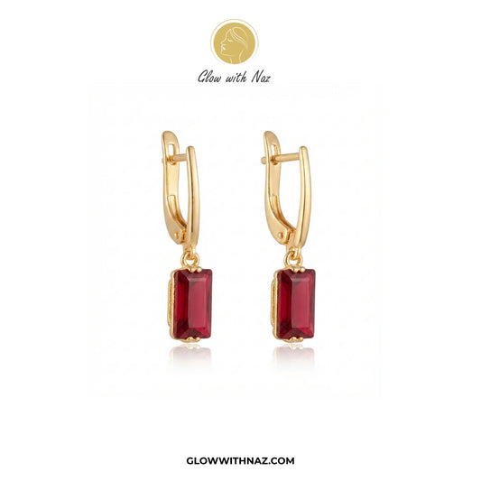 A pair of gold huggie hoop earrings with rectangular red gemstones, displayed on a clean white background with the brand logo 'Glow with Naz' at the top. studs earrings, small earrings, girls earrings, simple earrings, earrings for girls, black earrings, earrings, ear rings, earrings tops, stud earrings, tops earrings, aesthetic earrings, hoop earrings, drop earrings, diamond earrings, pink earrings, green earrings, ear ring, earrings for women, flower earrings, golden earrings, bali earrings, ear jewellery