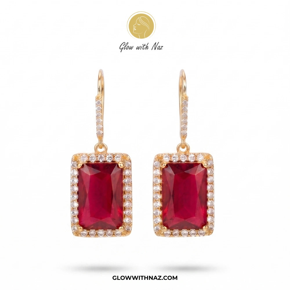 A pair of gold drop earrings featuring rectangular emerald-cut deep red gemstones surrounded by small clear stones, shown on a white background with Glow with Naz branding. studs earrings, small earrings, girls earrings, simple earrings, earrings for girls, black earrings, earrings, ear rings, earrings tops, stud earrings, tops earrings, aesthetic earrings, hoop earrings, drop earrings, diamond earrings, pink earrings, green earrings, ear ring, earrings for women, flower earrings, golden earrings, bali earr