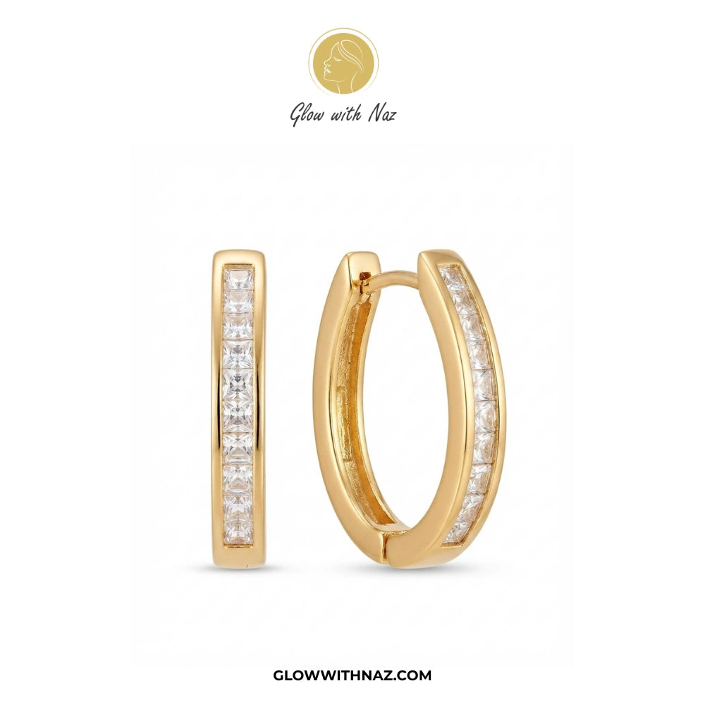 A pair of gold huggie hoop earrings with pavé-set clear stones, shown from two angles on a white background. The brand logo 'Glow with Naz' is visible at the top, and the website 'GLOWWITHNAZ. studs earrings, small earrings, girls earrings, simple earrings, earrings for girls, black earrings, earrings, ear rings, earrings tops, stud earrings, tops earrings, aesthetic earrings, hoop earrings, drop earrings, diamond earrings, pink earrings, green earrings, ear ring, earrings for women, flower earrings, golden