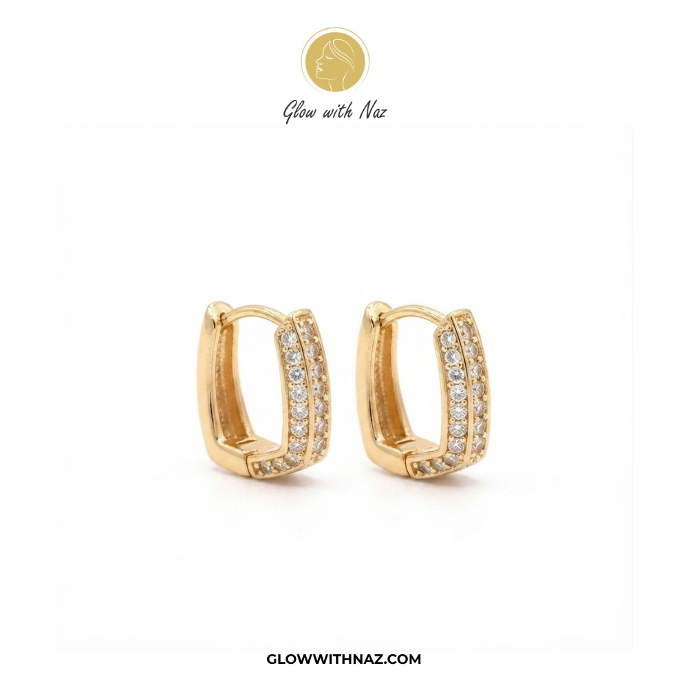 A pair of gold huggie hoop earrings with pavé-set clear stones, displayed on a clean white background with the brand logo 'Glow with Naz' at the top and the website 'GLOWWITHNAZ.COM' at the bottom. studs earrings, small earrings, girls earrings, simple earrings, earrings for girls, black earrings, earrings, ear rings, earrings tops, stud earrings, tops earrings, aesthetic earrings, hoop earrings, drop earrings, diamond earrings, pink earrings, green earrings, ear ring, earrings for women, flower earrings, g