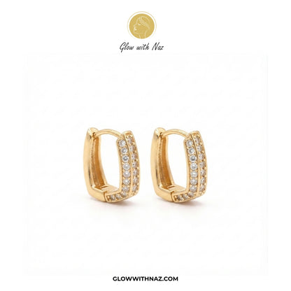 A pair of gold huggie hoop earrings with pavé-set clear stones, displayed on a clean white background with the brand logo 'Glow with Naz' at the top and the website 'GLOWWITHNAZ.COM' at the bottom. studs earrings, small earrings, girls earrings, simple earrings, earrings for girls, black earrings, earrings, ear rings, earrings tops, stud earrings, tops earrings, aesthetic earrings, hoop earrings, drop earrings, diamond earrings, pink earrings, green earrings, ear ring, earrings for women, flower earrings, g