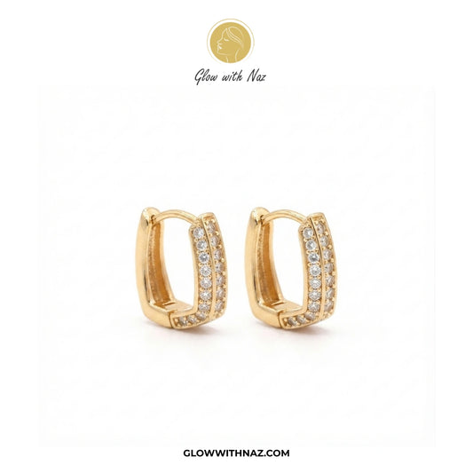 A pair of gold huggie hoop earrings with pavé-set clear stones, displayed on a clean white background with the brand logo 'Glow with Naz' at the top and the website 'GLOWWITHNAZ.COM' at the bottom. studs earrings, small earrings, girls earrings, simple earrings, earrings for girls, black earrings, earrings, ear rings, earrings tops, stud earrings, tops earrings, aesthetic earrings, hoop earrings, drop earrings, diamond earrings, pink earrings, green earrings, ear ring, earrings for women, flower earrings, g