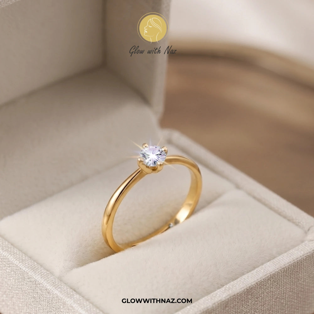A gold solitaire ring with a clear round gemstone displayed inside an open beige jewelry box. The brand name 'Glow with Naz' is visible as a watermark at the top and in the URL at the bottom. ring, girls rings, rings for girls, rings simple, simple rings, stainless steel jewelry, jewellery set, aesthetic jewelry, simple jewellery, chain, jewelry, artificial jewellery