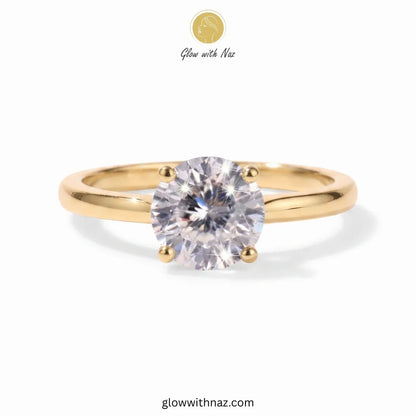 A yellow gold solitaire ring with a round brilliant-cut clear gemstone, shown on a white background with 'Glow with Naz' branding at the top. ring, girls rings, rings for girls, rings simple, simple rings, stainless steel jewelry, jewellery set, aesthetic jewelry, simple jewellery, chain, jewelry, artificial jewellery