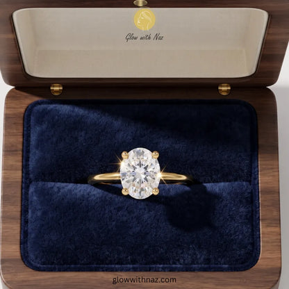 A yellow gold ring with a large round brilliant-cut diamond solitaire is displayed in an open wooden jewelry box with a dark blue velvet interior. The inside lid features the brand name 'Glow with Naz' in gold script on a cream background. ring, girls rings, rings for girls, rings simple, simple rings, stainless steel jewelry, jewellery set, aesthetic jewelry, simple jewellery, chain, jewelry, artificial jewellery