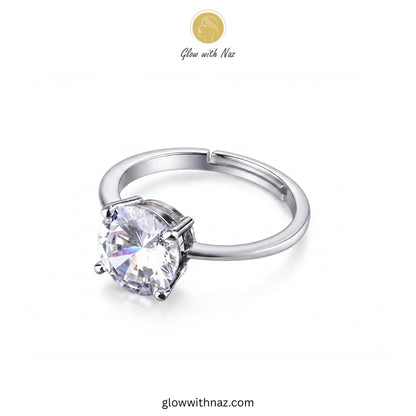 A silver-tone ring with a large round clear gemstone in a prong setting, shown on a plain white background. A small 'Glow with Naz' logo appears near the top, and 'glowwithnaz. ring, girls rings, rings for girls, rings simple, simple rings, stainless steel jewelry, jewellery set, aesthetic jewelry, simple jewellery, chain, jewelry, artificial jewellery