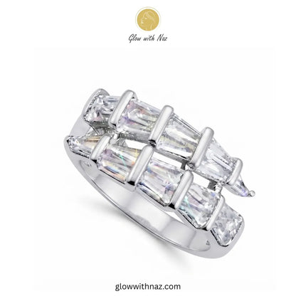 A silver-toned ring featuring multiple baguette and marquise-cut clear stones arranged in a geometric, interlocking pattern. The brand logo 'Glow with Naz' is visible at the top and the website 'glowwithnaz.