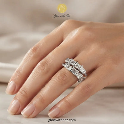 A close-up of a hand wearing a silver-toned ring with a row of clear baguette-cut gemstones. The image has 'Glow with Naz' branding at the top and 'glowwithnaz. ring, girls rings, rings for girls, rings simple, simple rings, stainless steel jewelry, jewellery set, aesthetic jewelry, simple jewellery, chain, jewelry, artificial jewellery
