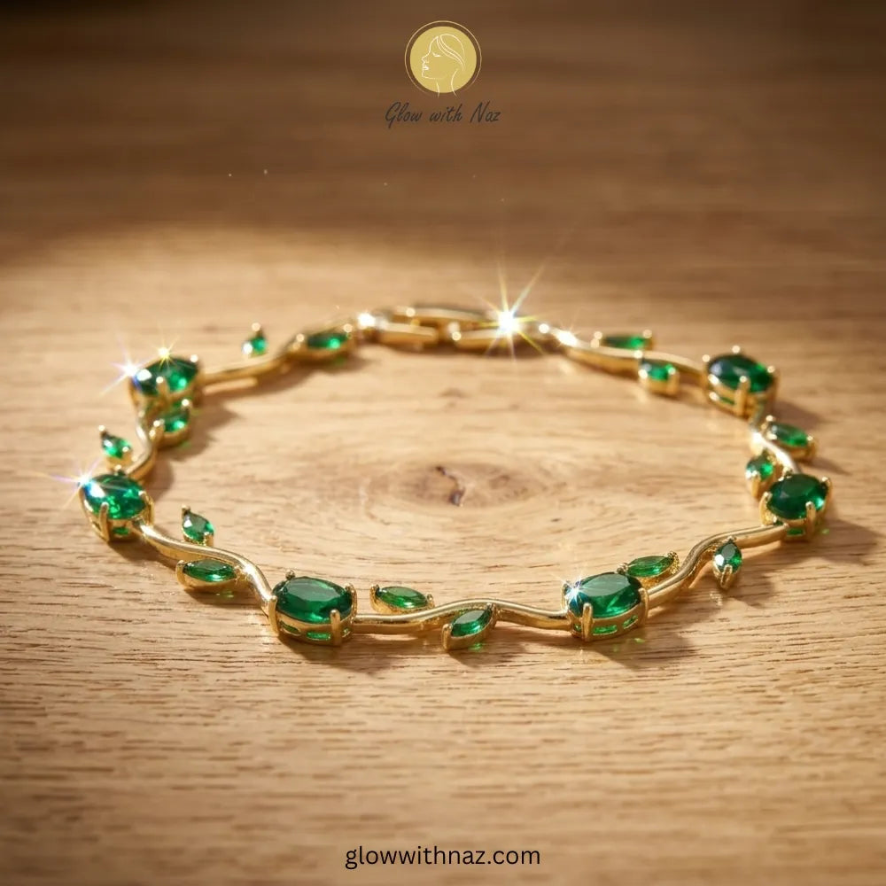 Gold bracelet with green gemstones on a wooden surface, branded 'Glow with Naz'. Tulip Rapunzel bracelet, floral tulip bracelet, Rapunzel inspired jewelry, aesthetic tulip bracelet, trendy charm bracelet, stainless steel tulip bracelet, gold plated flower bracelet, delicate floral wrist accessory, cute aesthetic jewelry, viral tulip bracelet, Rapunzel theme accessories, dainty floral bracelet, crystal tulip charm, stacking bracelets for women, minimalist floral jewelry, spring aesthetic bracelet, elegant tu