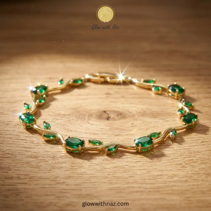Gold bracelet with green gemstones on a wooden surface, branded 'Glow with Naz'. Tulip Rapunzel bracelet, floral tulip bracelet, Rapunzel inspired jewelry, aesthetic tulip bracelet, trendy charm bracelet, stainless steel tulip bracelet, gold plated flower bracelet, delicate floral wrist accessory, cute aesthetic jewelry, viral tulip bracelet, Rapunzel theme accessories, dainty floral bracelet, crystal tulip charm, stacking bracelets for women, minimalist floral jewelry, spring aesthetic bracelet, elegant tu