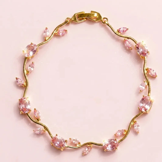 A gold vine bracelet adorned with marquise-cut pink gemstones, displayed on a soft pink background. Tulip Rapunzel bracelet, floral tulip bracelet, Rapunzel inspired jewelry, aesthetic tulip bracelet, trendy charm bracelet, stainless steel tulip bracelet, gold plated flower bracelet, delicate floral wrist accessory, cute aesthetic jewelry, viral tulip bracelet, Rapunzel theme accessories, dainty floral bracelet, crystal tulip charm, stacking bracelets for women, minimalist floral jewelry, spring aesthetic b